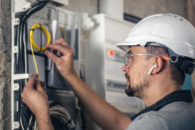 man electrical technician working switchboard with fuses
